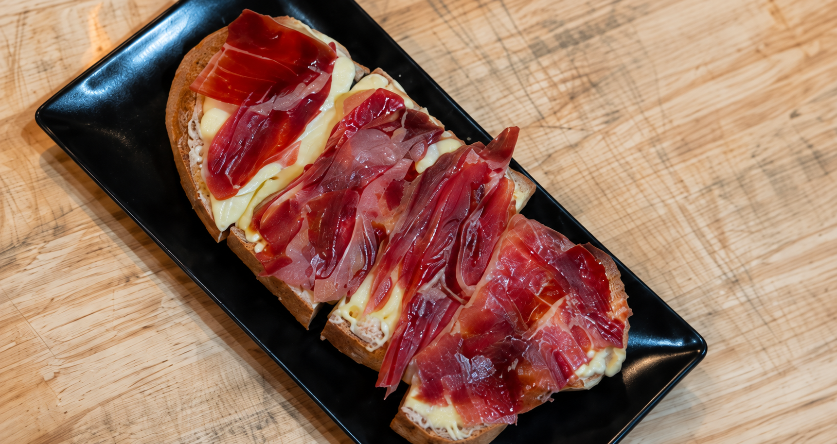 Tostas de jamón y queso sobre una bandeja negra